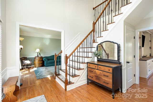 stairway featuring a towering ceiling and wood finished floors