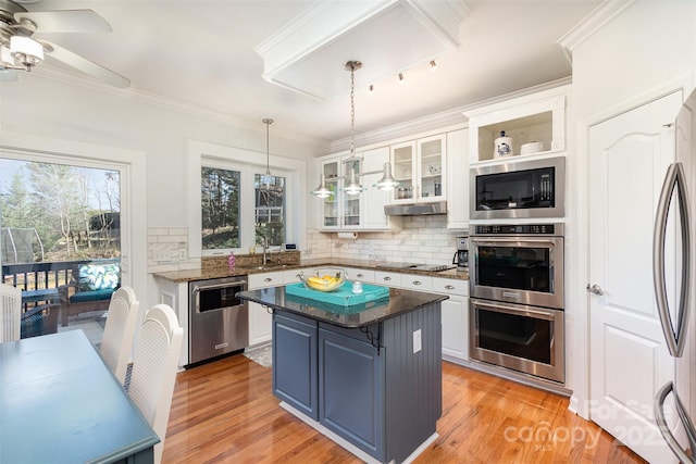 kitchen featuring stainless steel appliances, a sink, white cabinetry, ornamental molding, and blue cabinetry