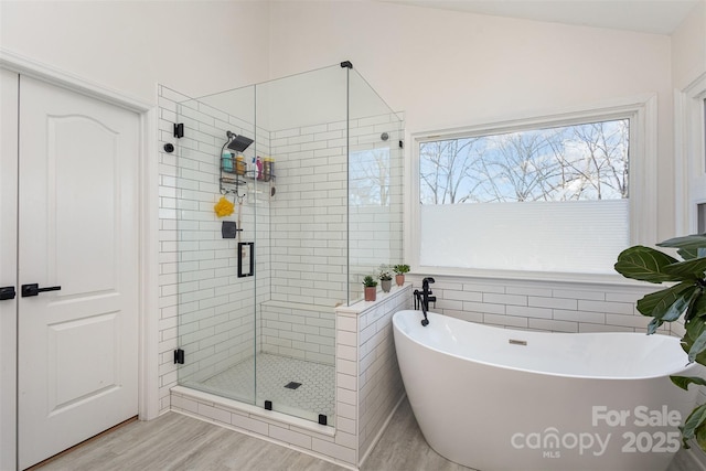 bathroom with a freestanding tub, a shower stall, and wood finished floors