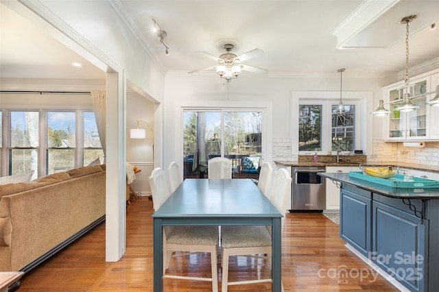 kitchen featuring dishwasher, dark countertops, glass insert cabinets, ornamental molding, and backsplash