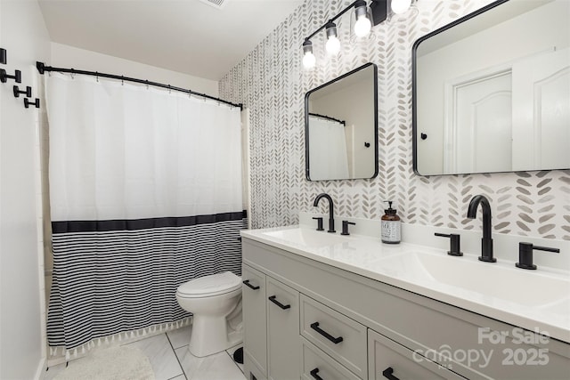 full bathroom featuring toilet, wallpapered walls, double vanity, and a sink