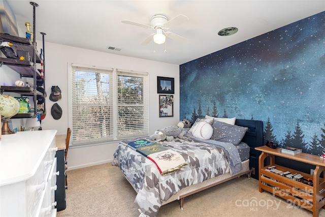 carpeted bedroom with visible vents, an accent wall, a ceiling fan, baseboards, and wallpapered walls