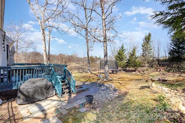 view of yard with a trampoline and a wooden deck