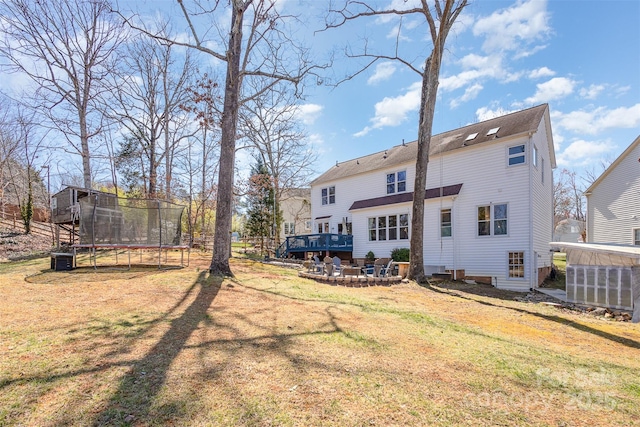 rear view of property featuring a trampoline and a yard