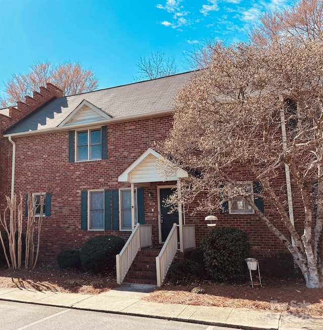 view of front facade featuring a shingled roof and brick siding