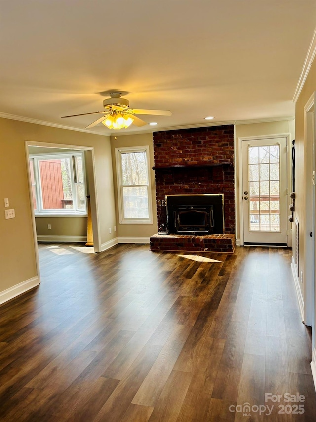 unfurnished living room featuring dark wood-style floors, ornamental molding, baseboards, and a healthy amount of sunlight