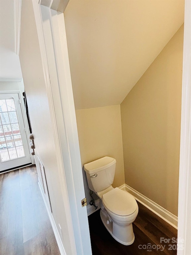 bathroom with lofted ceiling, wood finished floors, toilet, and baseboards