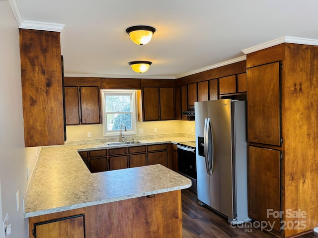 kitchen with dark wood-style flooring, light countertops, appliances with stainless steel finishes, a sink, and a peninsula