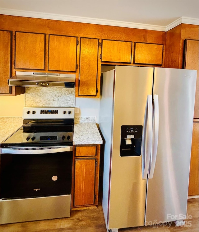 kitchen with dark wood-style floors, appliances with stainless steel finishes, brown cabinets, light countertops, and under cabinet range hood