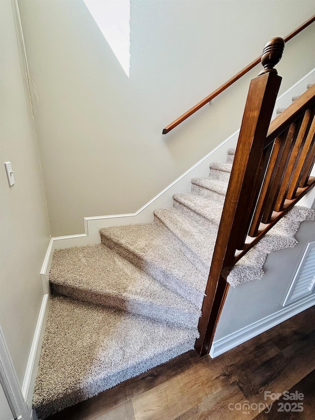 stairway with wood finished floors and baseboards