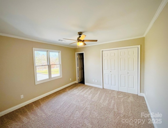 unfurnished bedroom with carpet, crown molding, a closet, ceiling fan, and baseboards