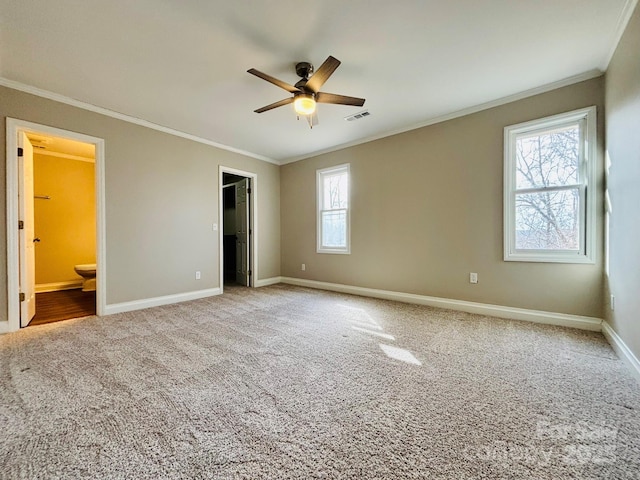 unfurnished bedroom featuring visible vents, baseboards, a spacious closet, ornamental molding, and carpet