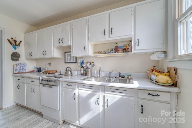 kitchen with a sink, white cabinets, white electric range, and light countertops