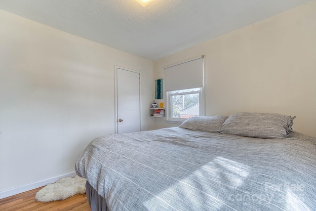 bedroom featuring a textured ceiling, wood finished floors, and baseboards