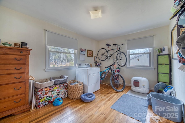 laundry area with light wood-type flooring, washer / dryer, laundry area, and baseboards