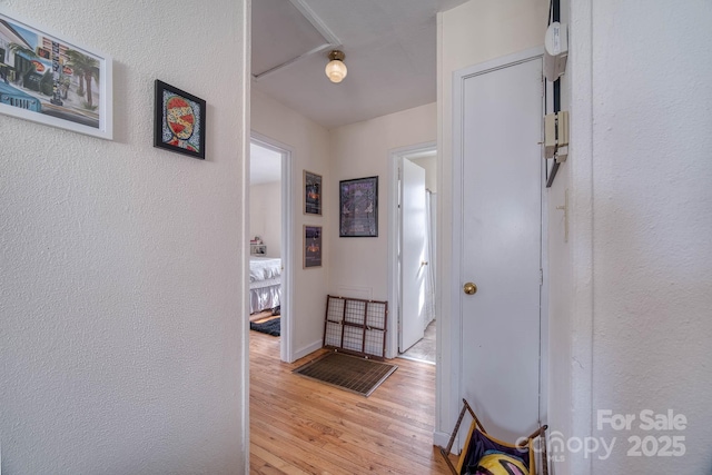 hall with light wood-style floors and a textured wall