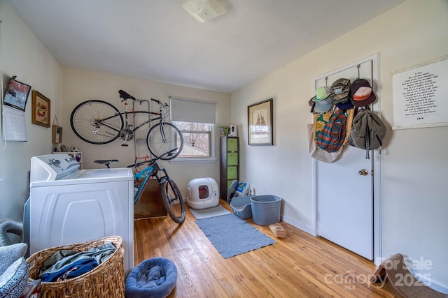 washroom with laundry area, baseboards, wood finished floors, and washing machine and clothes dryer