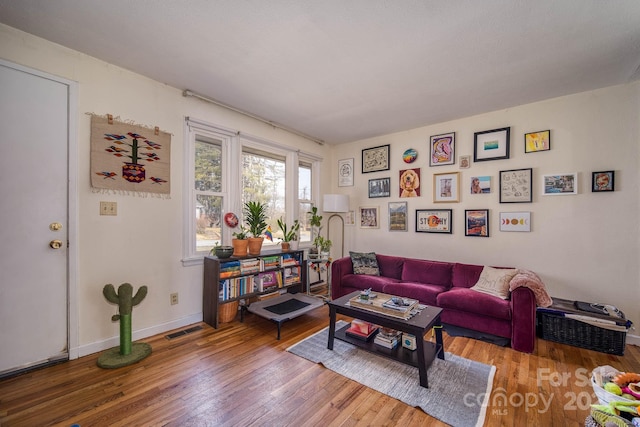 living room with visible vents, baseboards, and wood finished floors