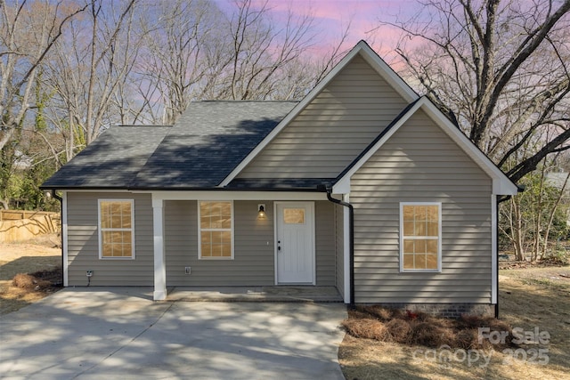 view of front of home featuring roof with shingles and fence