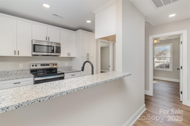 kitchen featuring visible vents, white cabinetry, and stainless steel appliances