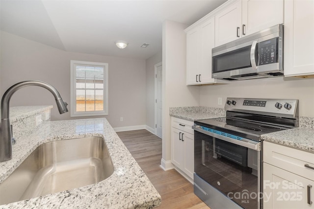 kitchen featuring appliances with stainless steel finishes, light stone counters, and a sink