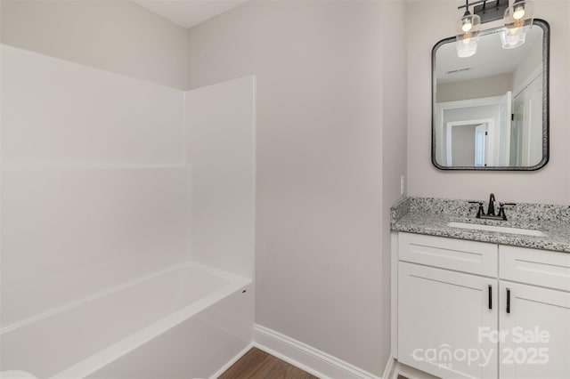 bathroom featuring shower / bath combination, baseboards, wood finished floors, and vanity