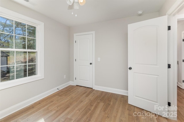 unfurnished bedroom with light wood-type flooring, visible vents, baseboards, and ceiling fan