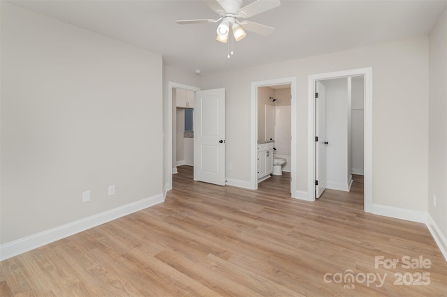 unfurnished bedroom featuring a walk in closet, a closet, ensuite bath, light wood-type flooring, and baseboards