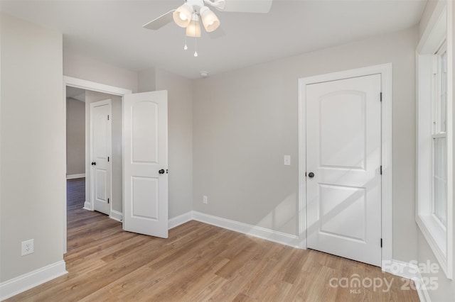 unfurnished bedroom with ceiling fan, light wood-style flooring, and baseboards