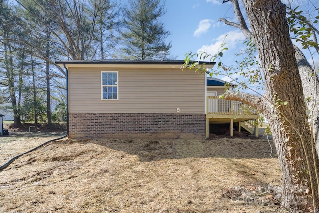 view of side of property featuring brick siding, a wooden deck, and stairs