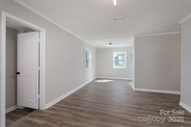 unfurnished room featuring dark wood-style floors, baseboards, visible vents, and ornamental molding