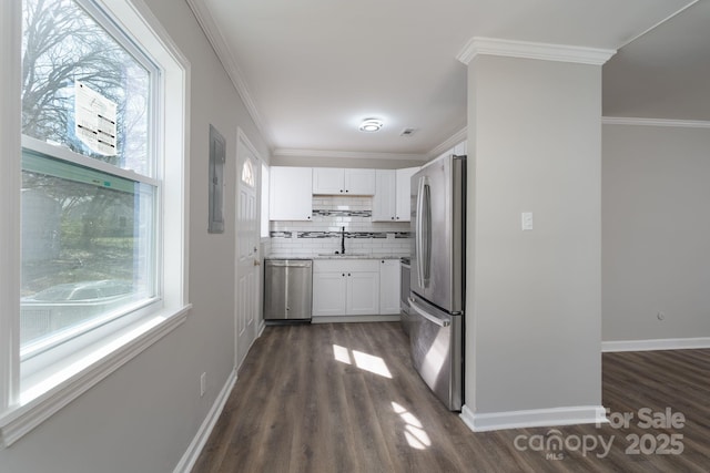 kitchen featuring light countertops, appliances with stainless steel finishes, ornamental molding, white cabinetry, and a sink