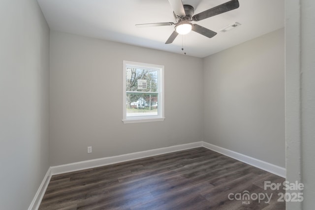 spare room featuring dark wood-type flooring, visible vents, ceiling fan, and baseboards