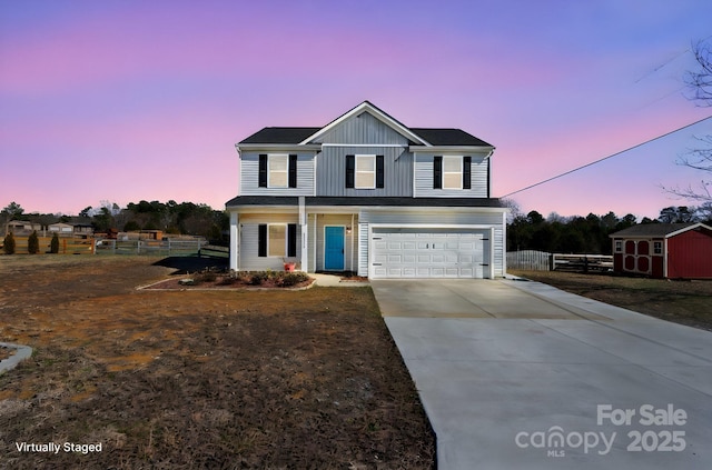 traditional home featuring an attached garage, fence, concrete driveway, a storage unit, and board and batten siding