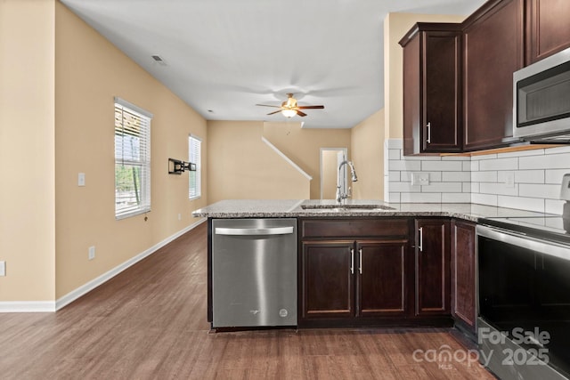 kitchen featuring appliances with stainless steel finishes, dark wood-style flooring, a sink, and backsplash