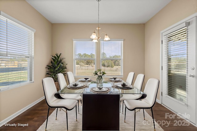 dining space with dark wood-style floors, baseboards, a wealth of natural light, and an inviting chandelier