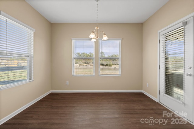 unfurnished dining area featuring dark wood-style floors, a notable chandelier, and a wealth of natural light