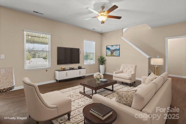 living room with dark wood-style flooring, plenty of natural light, visible vents, and baseboards