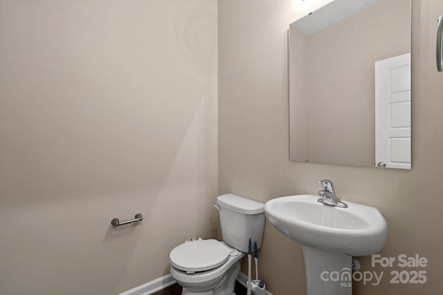 half bath with baseboards and toilet