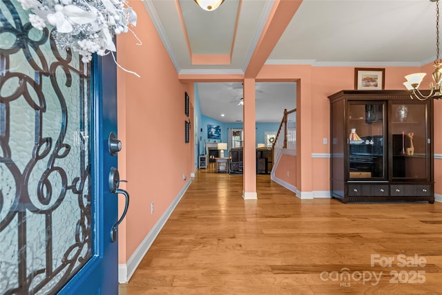 foyer featuring ornamental molding, light wood finished floors, ceiling fan with notable chandelier, and baseboards