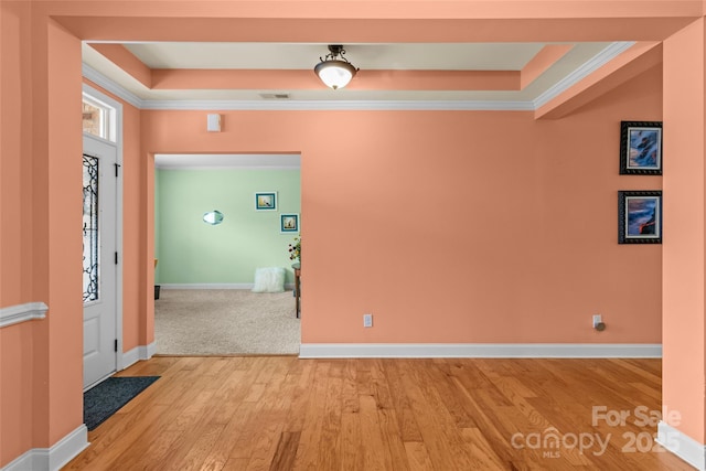 interior space featuring a tray ceiling, crown molding, visible vents, light wood-style flooring, and baseboards