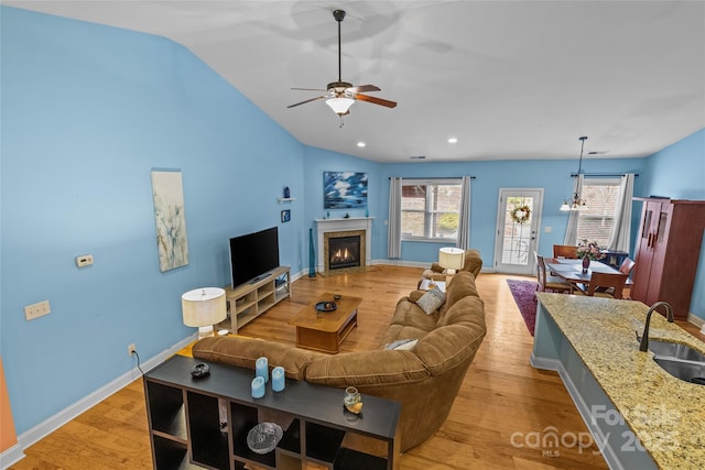 living room with lofted ceiling, light wood finished floors, a glass covered fireplace, and recessed lighting