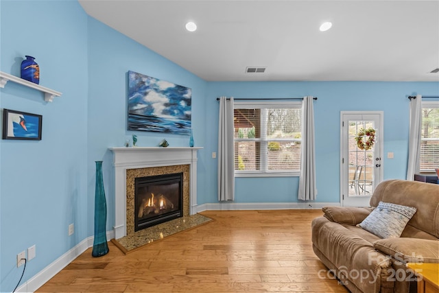 living area with baseboards, wood finished floors, and a high end fireplace