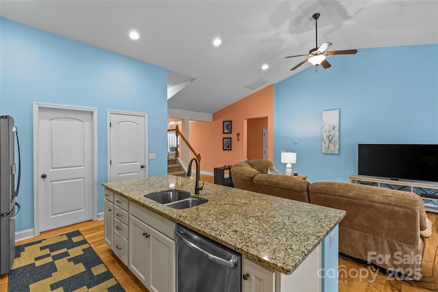 kitchen featuring lofted ceiling, a sink, white cabinetry, open floor plan, and appliances with stainless steel finishes