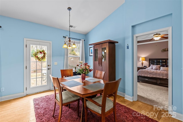 dining space featuring light wood-style flooring, visible vents, vaulted ceiling, and baseboards