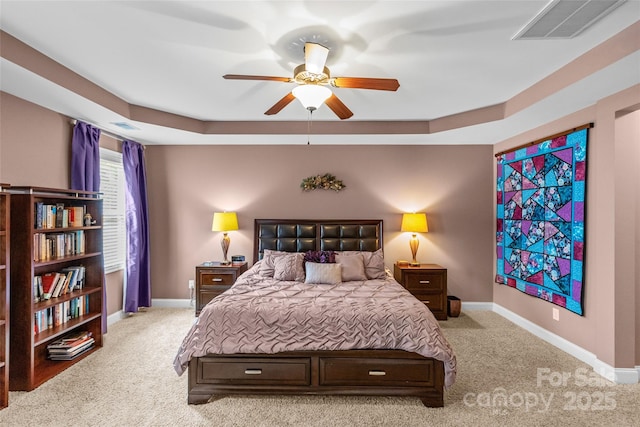 bedroom with a tray ceiling, carpet flooring, visible vents, and baseboards