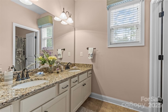 bathroom with double vanity, baseboards, a sink, and tile patterned floors