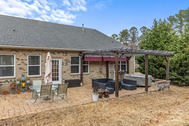 rear view of property with brick siding, roof with shingles, a patio area, a pergola, and a jacuzzi