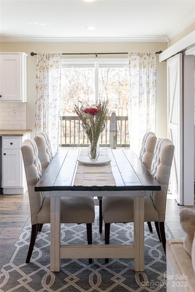 dining area with ornamental molding, wood finished floors, and a healthy amount of sunlight