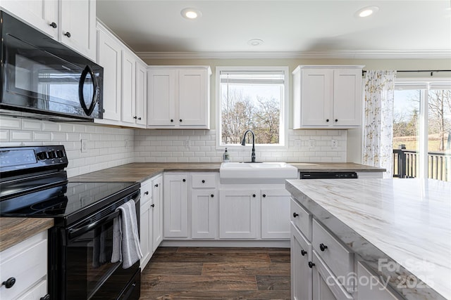 kitchen with black appliances, white cabinetry, wooden counters, and a sink